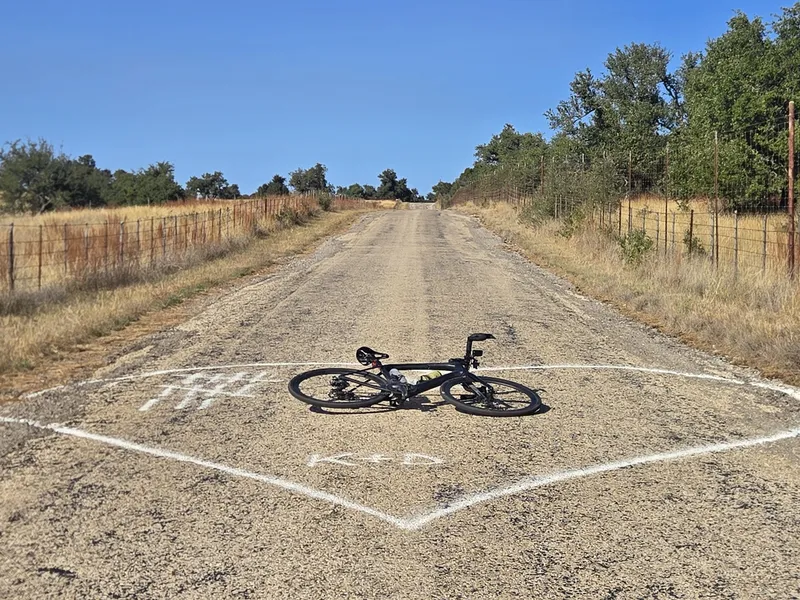 A bike lying inside a heart painted on a country road.