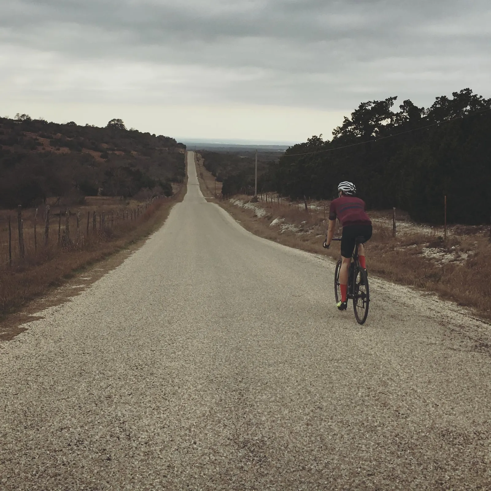 A rider on a long, straight Hill Country road.